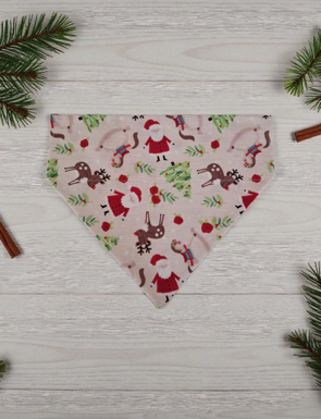 Triangular bandana with Christmas-themed pattern on a wooden surface with cinnamon sticks and pine branches.